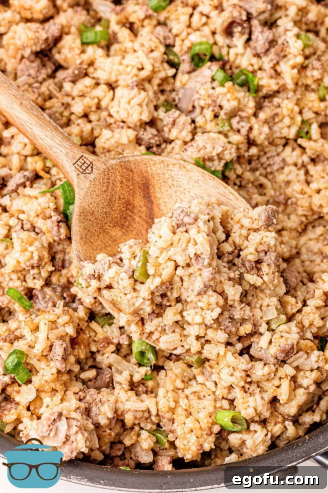 Close-up of a wooden spoon scooping perfectly seasoned Dirty Rice from a pan, showcasing the rich, earthy brown color and tender texture of the dish.