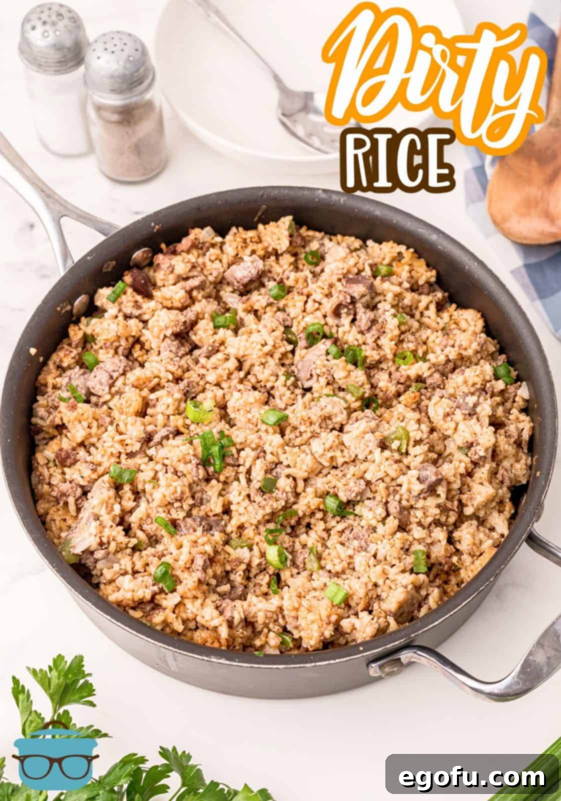 A large skillet brimming with a freshly prepared batch of Dirty Rice, garnished with vibrant green onions, ready to be served family style and enjoyed.