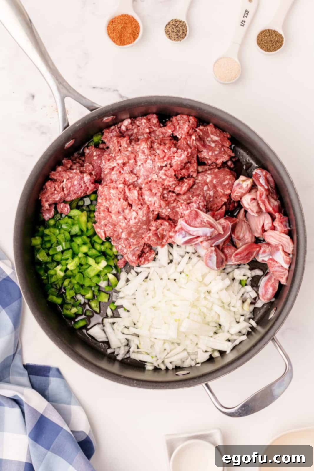 Ground beef, chicken gizzards, chopped bell pepper, diced onion, and minced garlic sizzling and browning together in a large skillet, building the savory core of Dirty Rice.