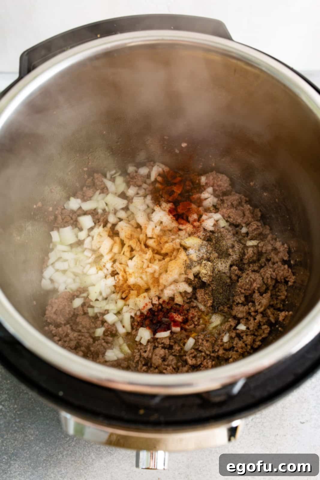 Instant Pot Creamy Beef and Noodle Stroganoff 5 Cooked ground beef in instant pot with onions and dry seasonings added.