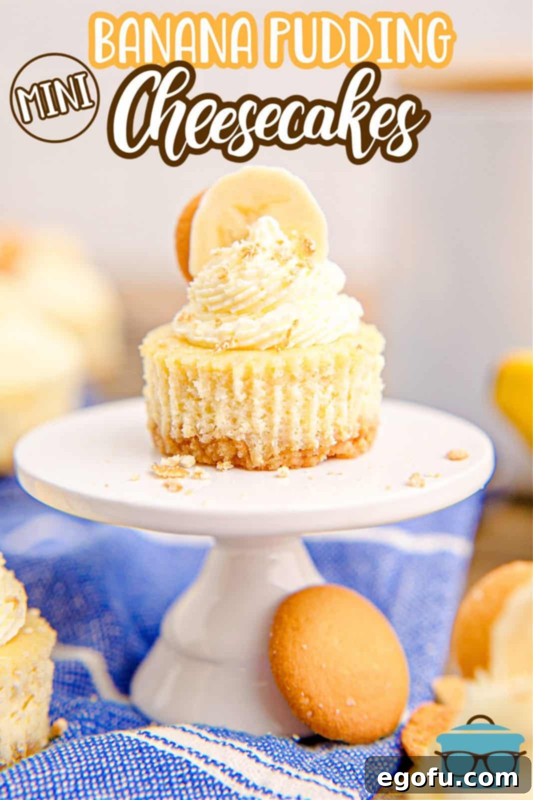 Pinterest image of decorated Mini Banana Pudding Cheesecake on white stand with cheesecakes behind it, showcasing their appeal.