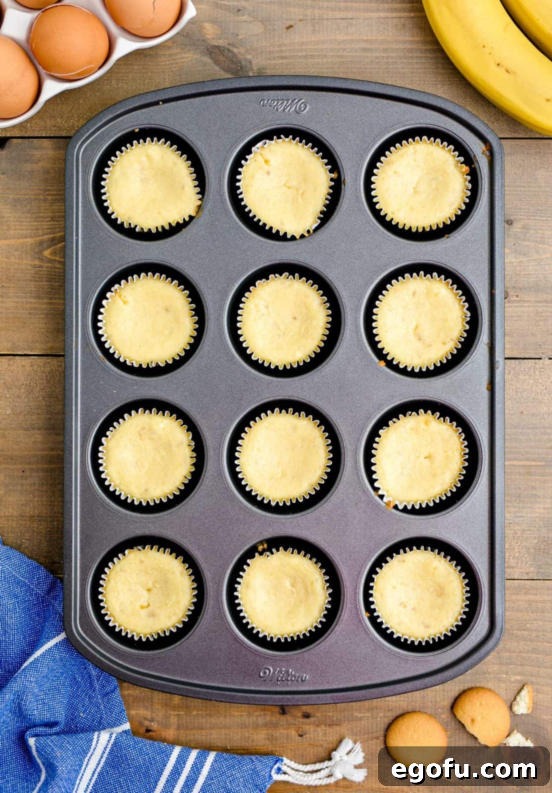 Fully Baked Mini Banana Pudding Cheesecakes resting in a muffin tin, showing their golden brown tops.
