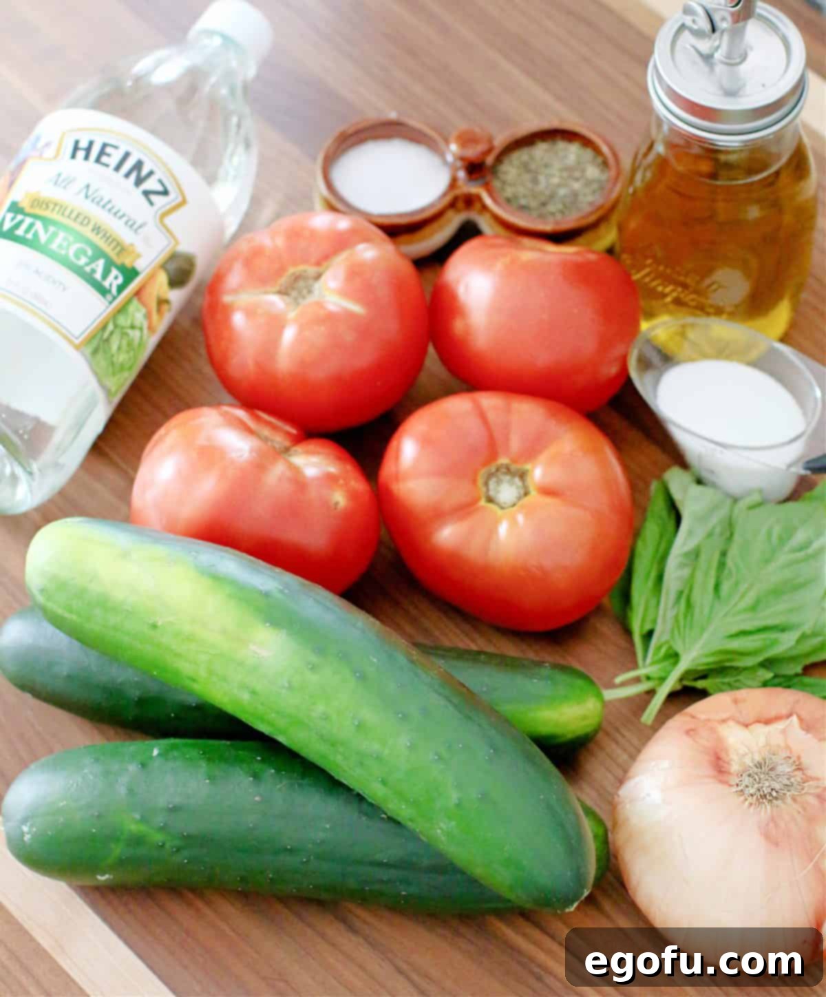 Ingredients needed for Marinated Tomato Cucumber Salad: cucumbers, tomatoes, sweet onion, white vinegar, water, olive oil, granulated sugar, kosher salt, freshly ground black pepper, and fresh basil leaves.