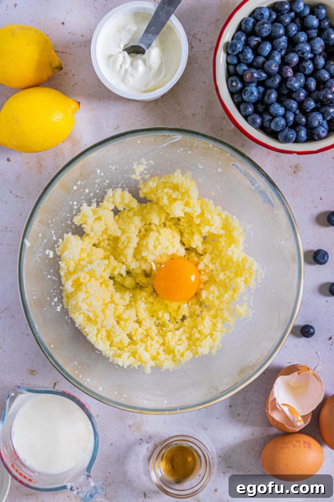 Sugar and butter beaten together with egg added on top in a clear bowl.