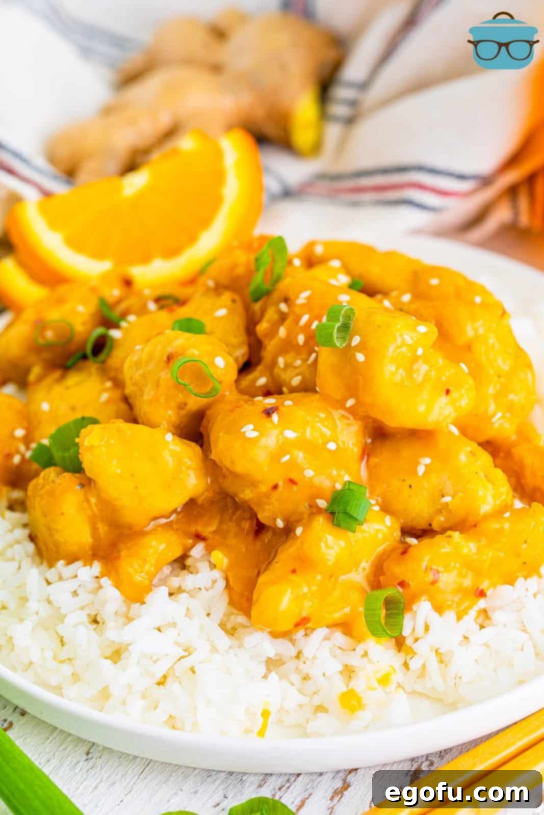 Golden Air Fryer Orange Chicken Delight 2 air fryer orange chicken shown on a bed of white rice on a round white plate.
