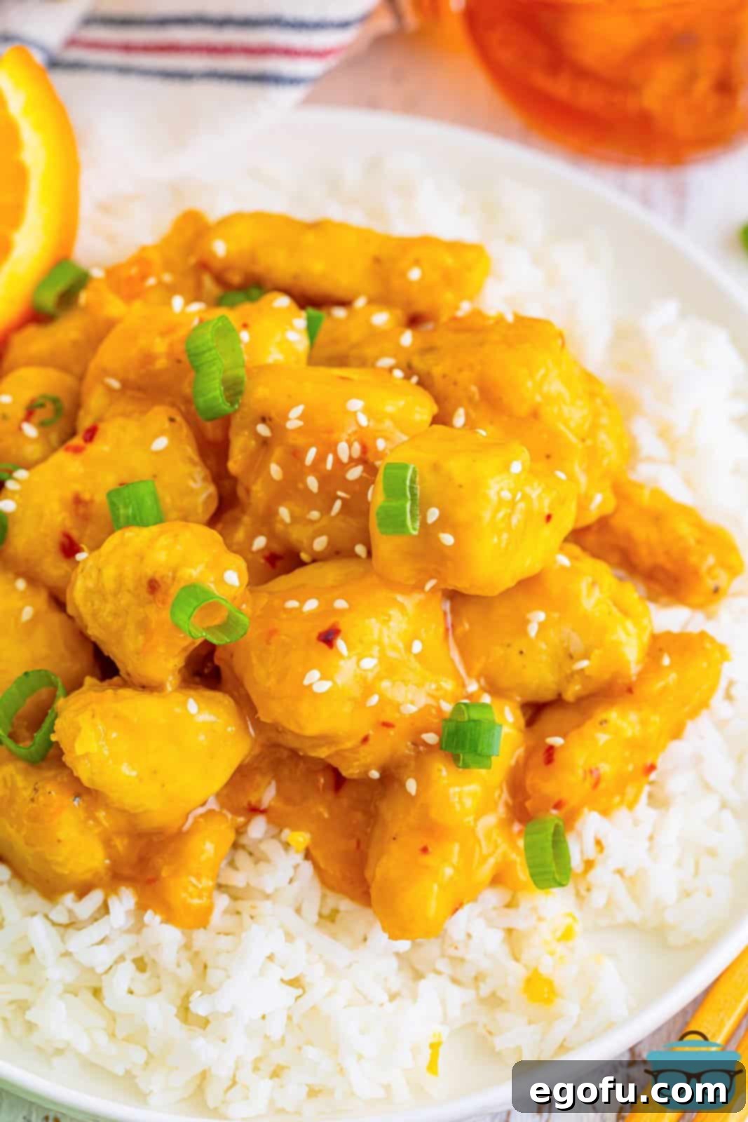 Golden Air Fryer Orange Chicken Delight 8 air fryer orange chicken on white rice with a glass of iced tea in the background.