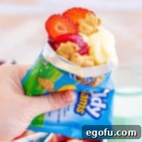 The Wandering Strawberry Cheesecake 12 Square image of hand holding a bag of Walking Strawberry Cheesecakes with filling coming out of the top