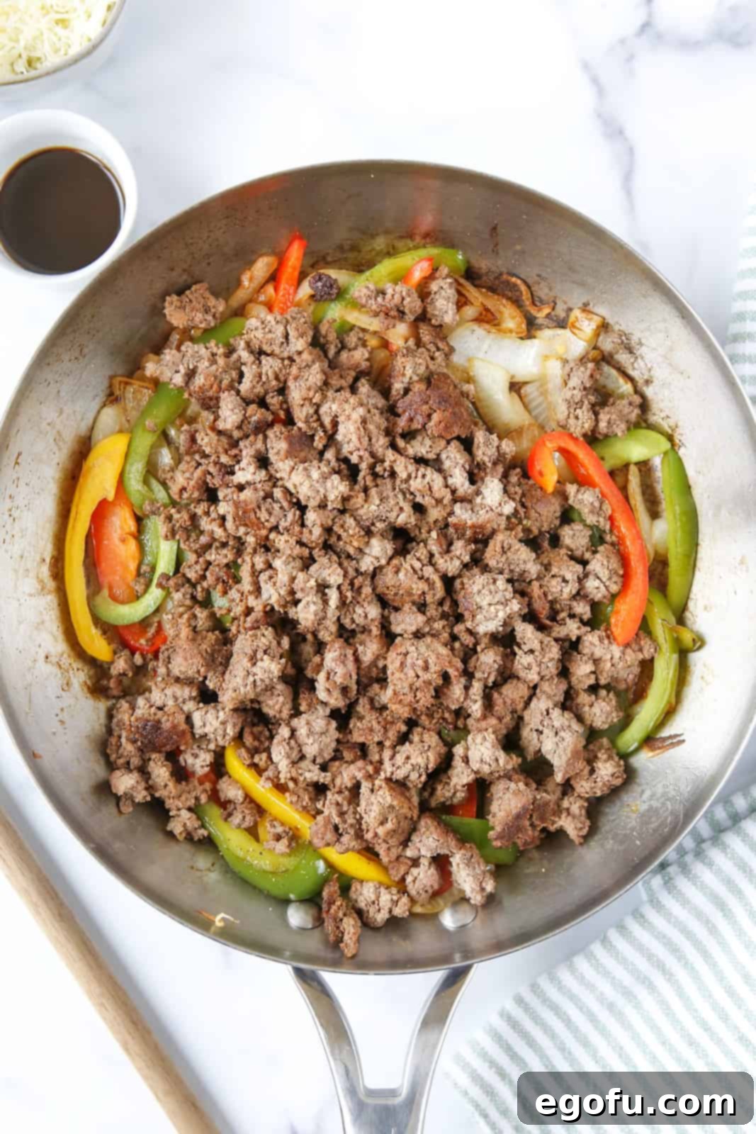 One-Pan Philly Cheesesteak Feast 9 cooked ground beef, seasonings, broth and Worcestershire sauce added to skillet with vegetables.