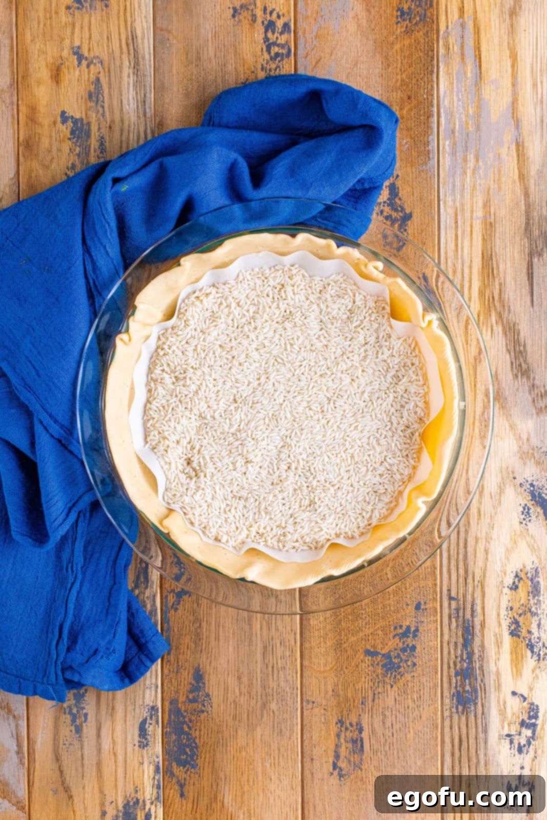Effortless Taco Bake 5 rice added on top of parchment paper on top of pie crust.