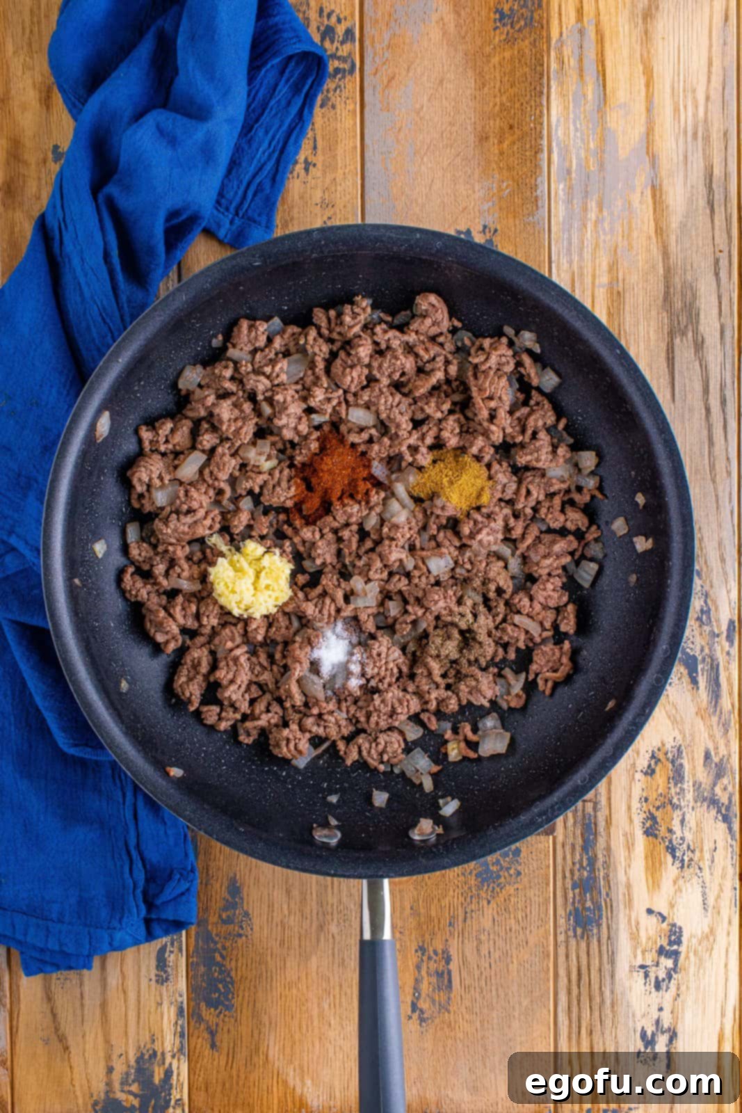 Effortless Taco Bake 7 taco seasonings and garlic added to cooked ground beef in skillet.