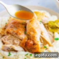 Square image of spoon dripping gravy over chicken on plate.