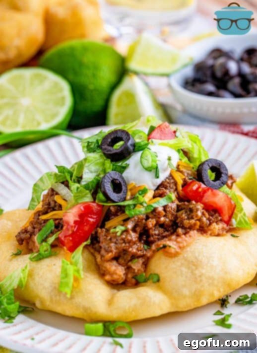 Fry Bread Taco on white plate topped with taco toppings.