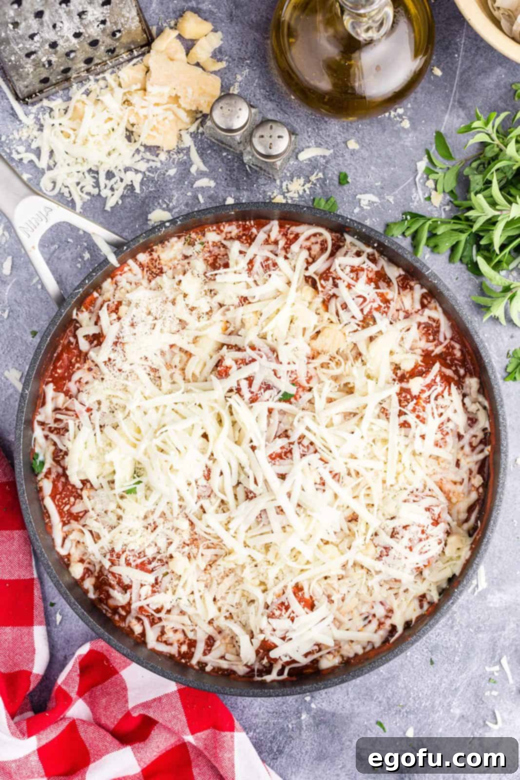 Easy Cheesy Skillet Meatballs 6 Grated mozzarella and parmesan cheese generously topping meatballs and marinara sauce in a skillet, ready for baking.