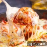 Easy Cheesy Skillet Meatballs 9 Square image of a meatball being pulled up from the Meatball Parmesan Skillet with cheese.