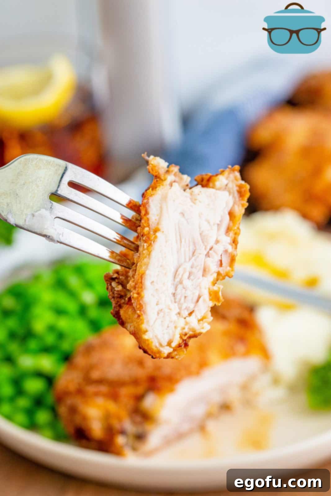Fork holding up a bite of Air Fryer Chicken Thighs. Close up of the crispy skin and tender meat.