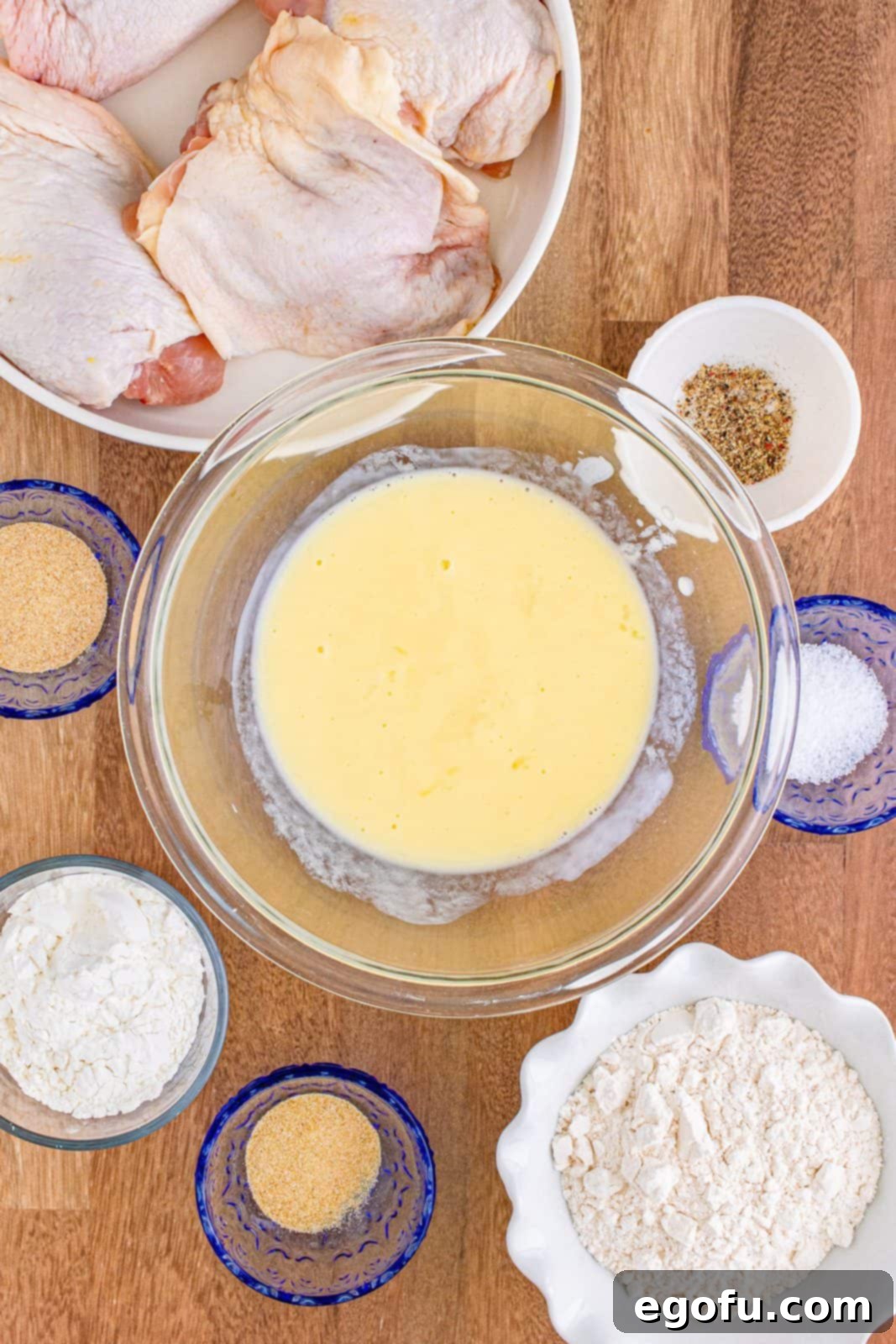 Buttermilk and egg whisked together in glass bowl. A clear glass bowl containing the creamy mixture.