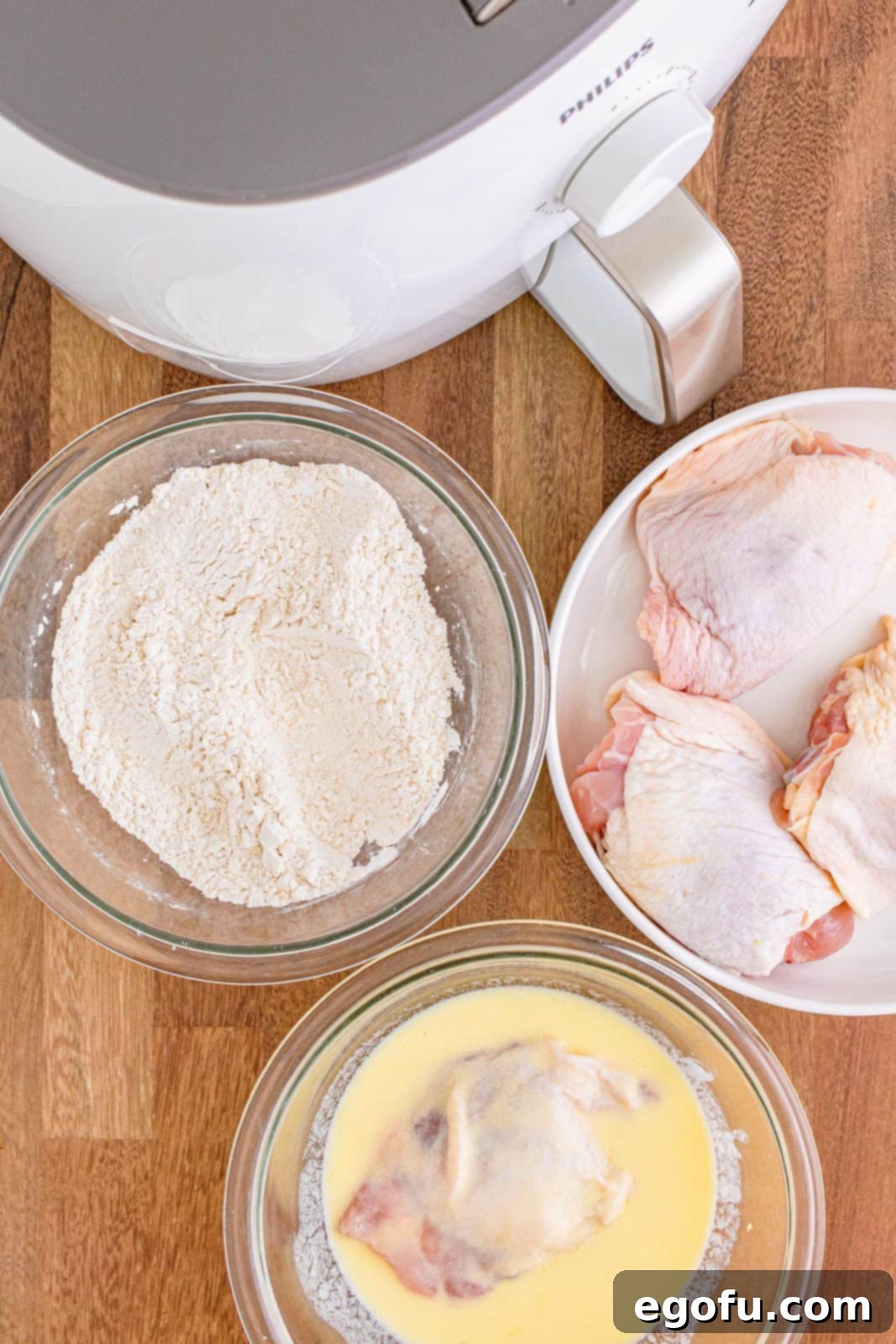 Chicken being dipped in wet and dry ingredients. Hands coating chicken in flour.