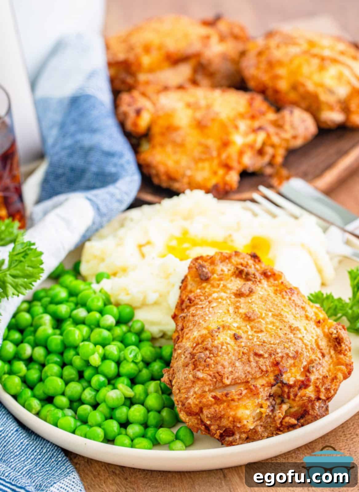 One piece of Air Fried Chicken on plate with peas and potatoes. A single serving ready to eat.