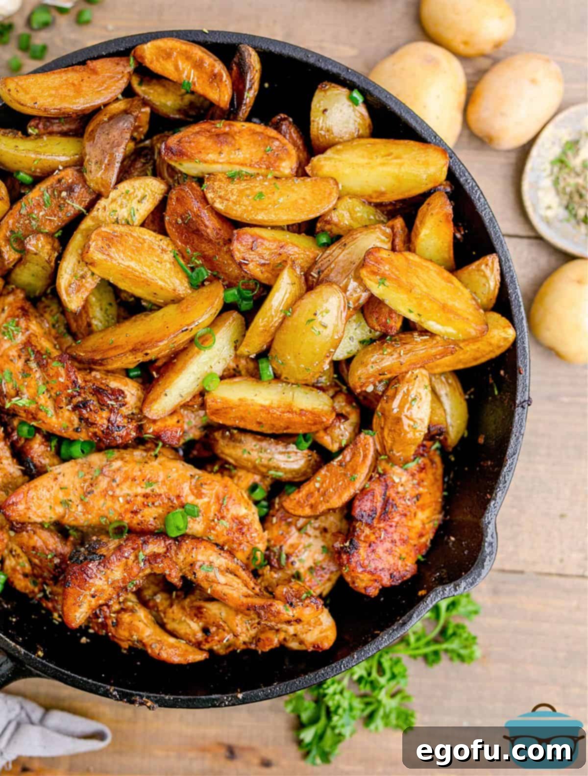Golden Garlic Butter Chicken and Crispy Potatoes 2 Overhead shot of freshly cooked Garlic Butter Chicken and Potatoes in a cast-iron skillet, garnished with vibrant green parsley, ready to be served.