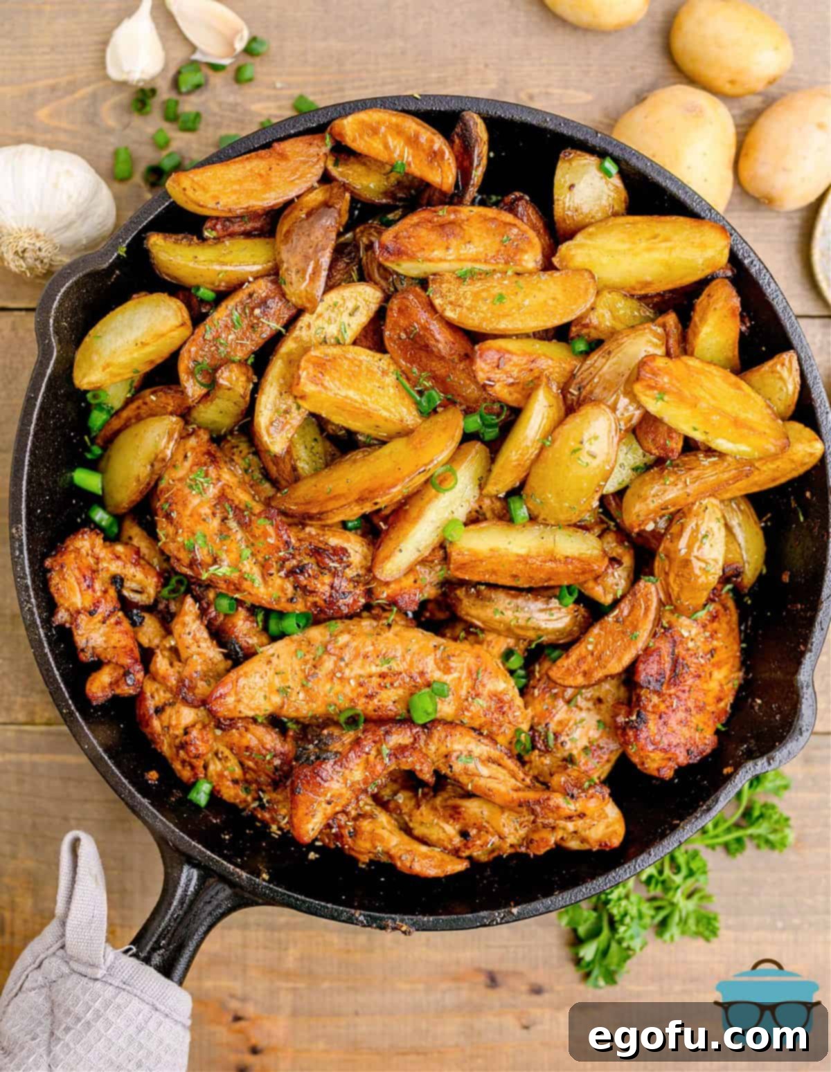 Golden Garlic Butter Chicken and Crispy Potatoes 13 Finished Garlic Butter Chicken and Potatoes, beautifully arranged in a cast-iron skillet, with a kitchen towel wrapped around the handle for serving.