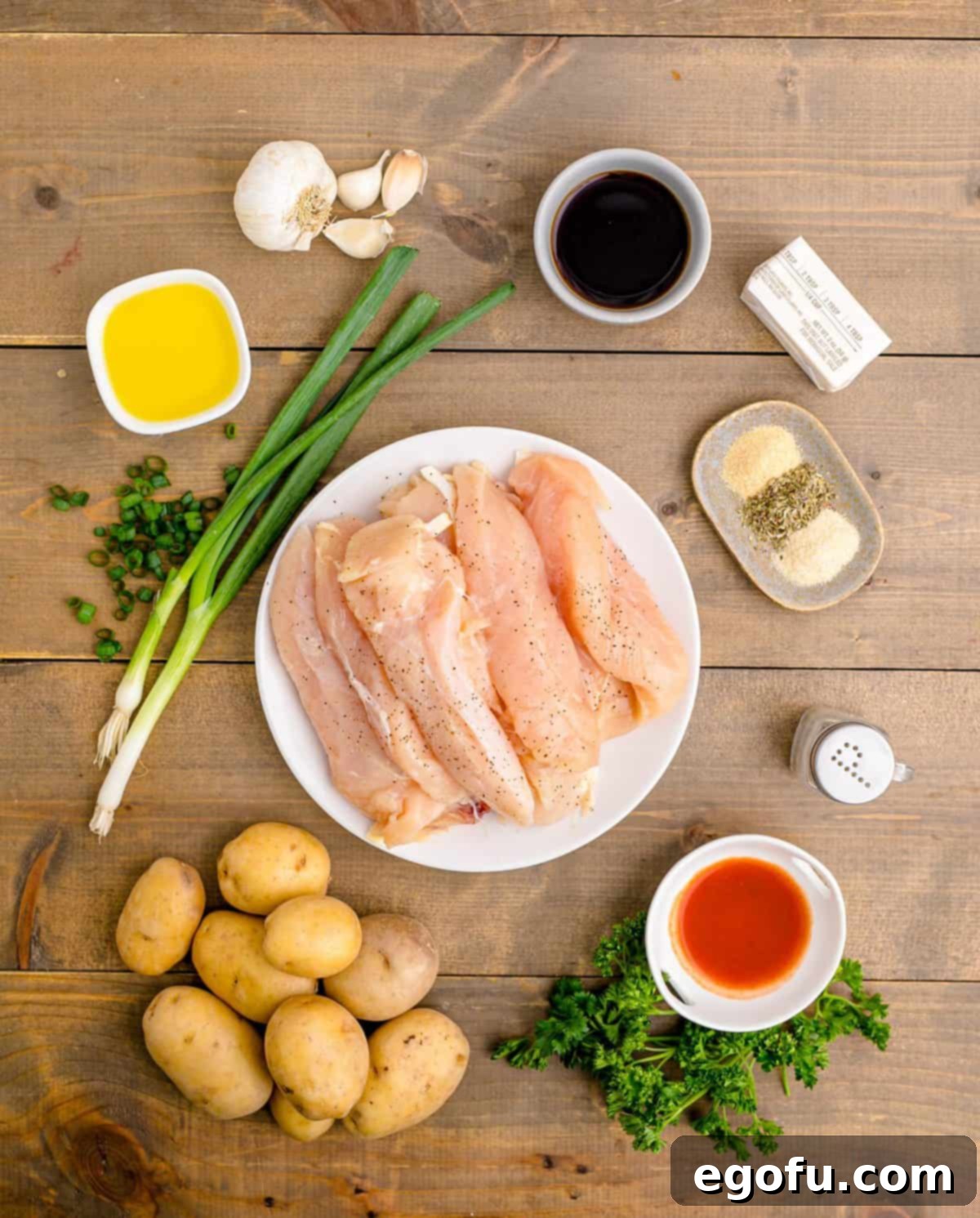 Golden Garlic Butter Chicken and Crispy Potatoes 4 A selection of fresh ingredients laid out on a wooden board, including chicken tenderloins, baby gold potatoes, garlic, butter, and seasonings, ready for the Garlic Butter Chicken and Potatoes recipe.