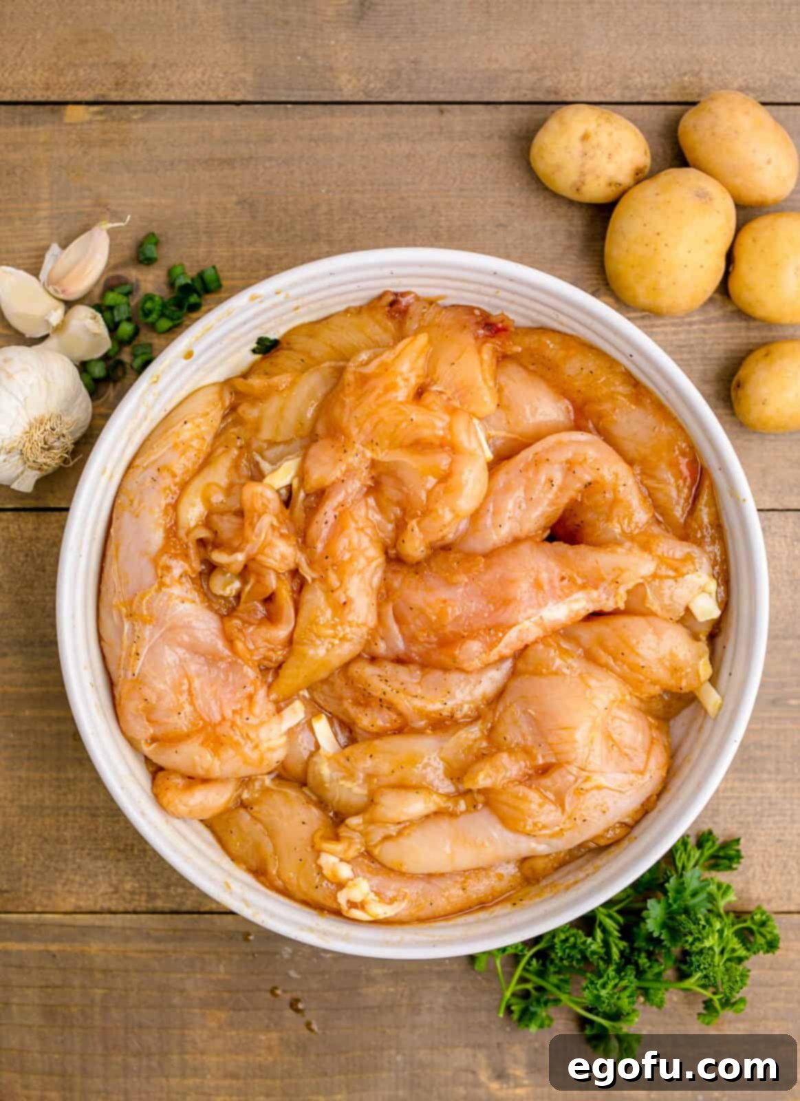 Golden Garlic Butter Chicken and Crispy Potatoes 5 Chicken tenderloins marinating in a bowl with soy sauce, olive oil, hot sauce, pepper, garlic powder, and onion powder.