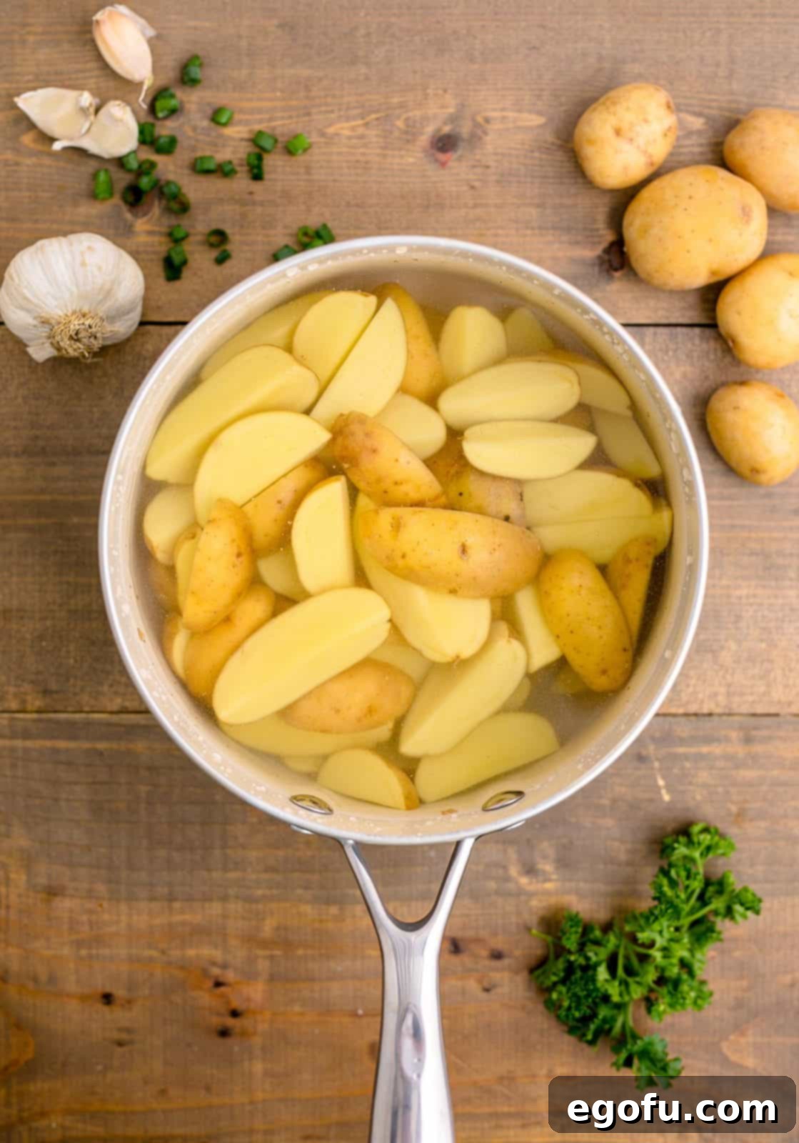 Golden Garlic Butter Chicken and Crispy Potatoes 7 Quartered potatoes being par-boiled in a pot of salted boiling water on a stovetop.