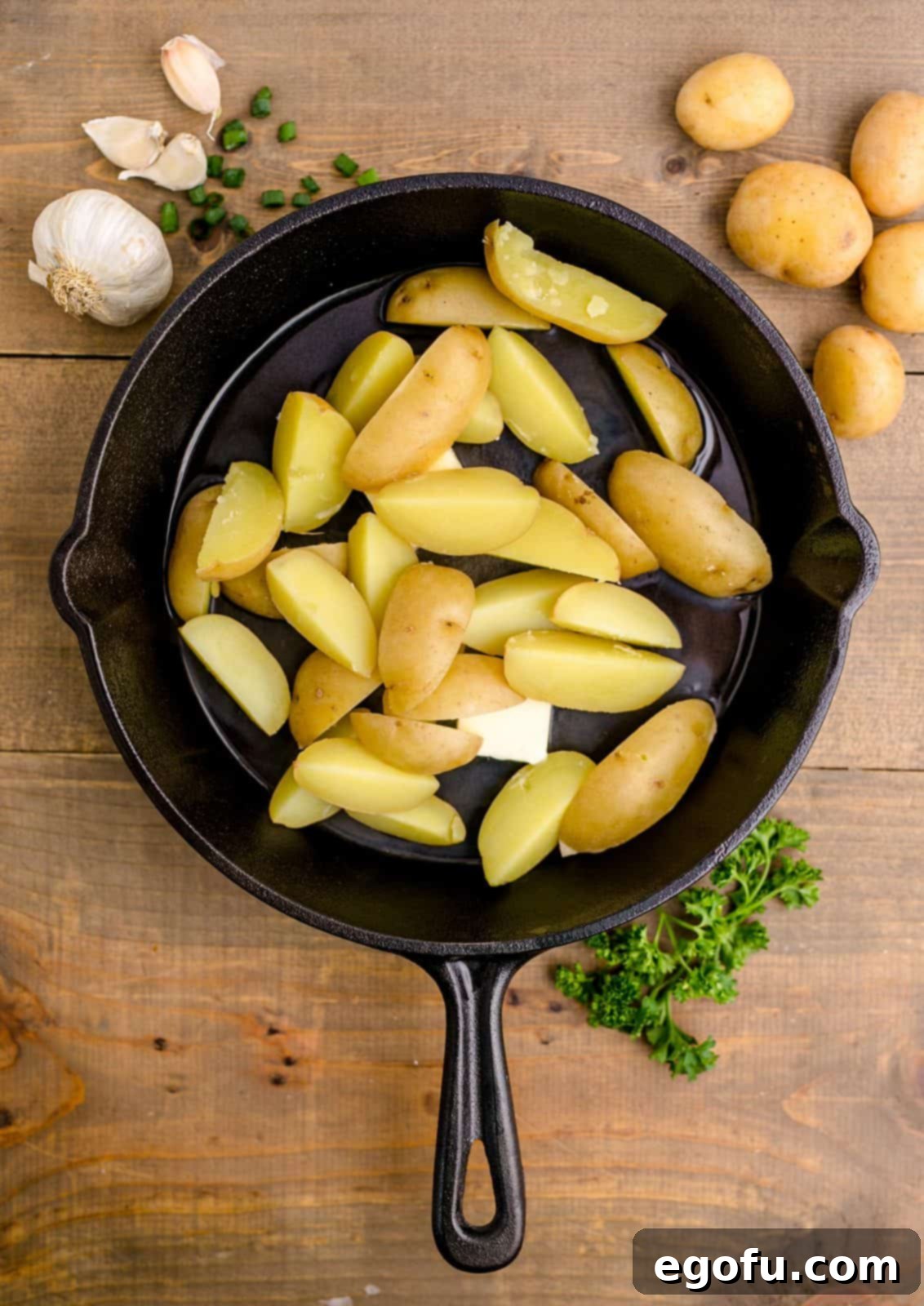 Golden Garlic Butter Chicken and Crispy Potatoes 9 Butter, a hint of garlic, and quartered potatoes added to a hot cast-iron skillet, beginning to sizzle.