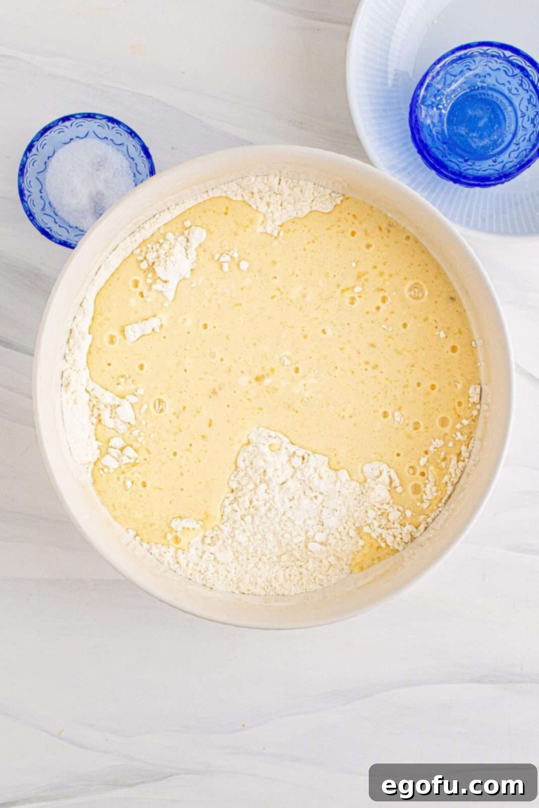 The wet pancake batter mixture being carefully poured into the bowl of dry ingredients, ready for combining.