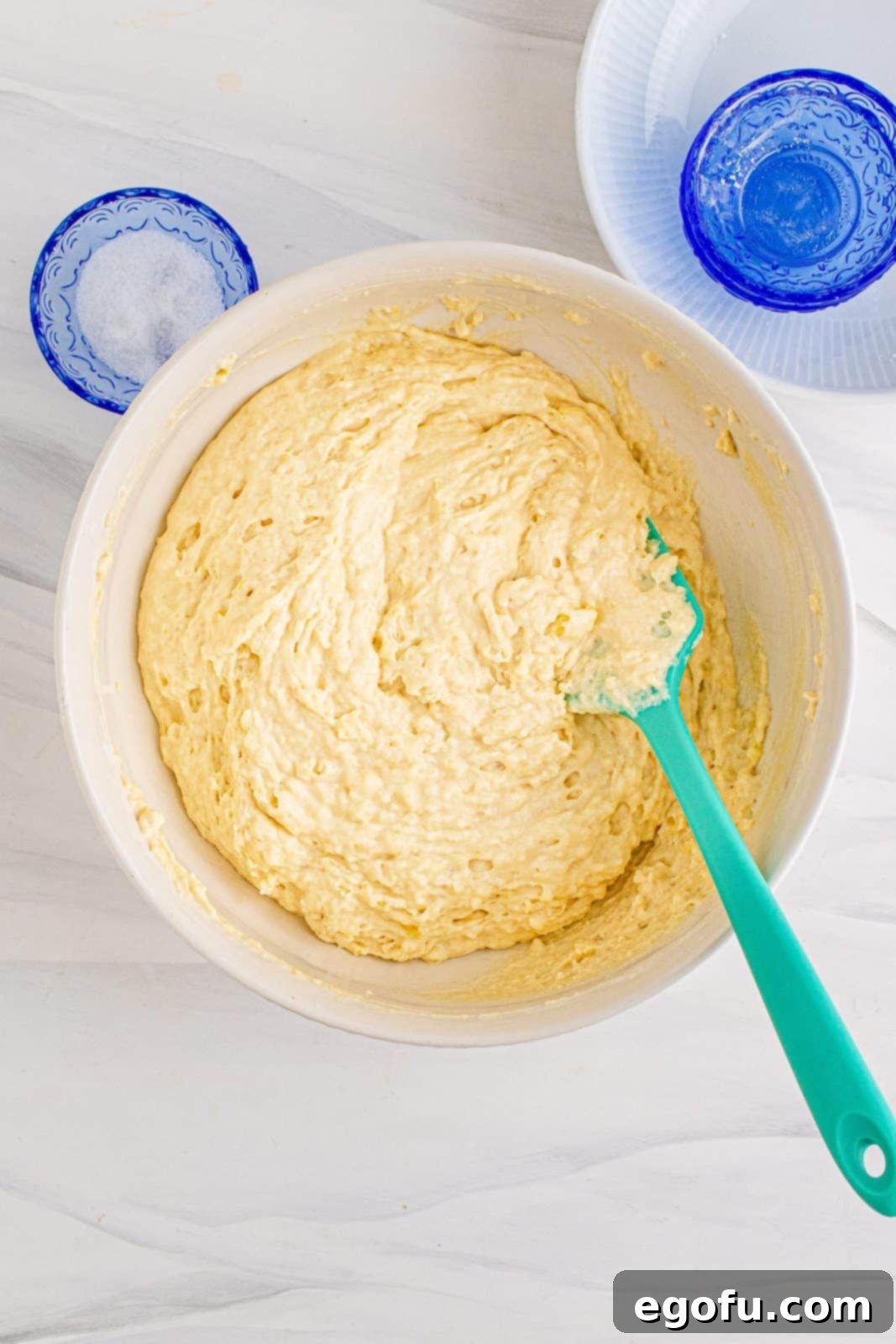 Freshly mixed pancake batter in a white bowl, showing a slightly lumpy but smooth consistency, ready for the sheet pan.