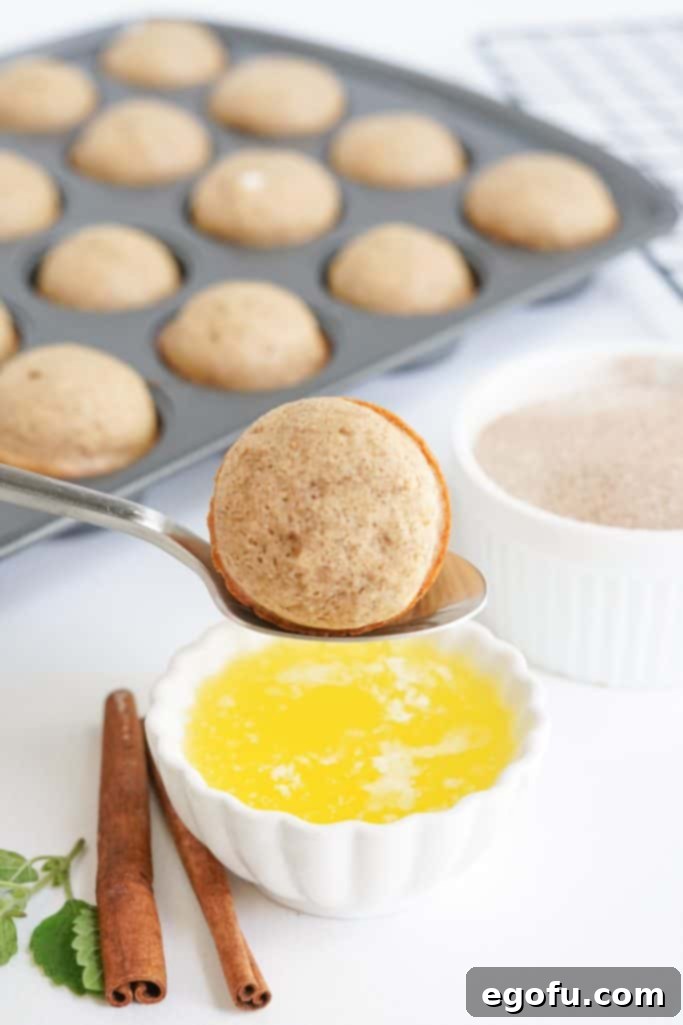 Donut being held by spoon ready to be dipped in melted butter.