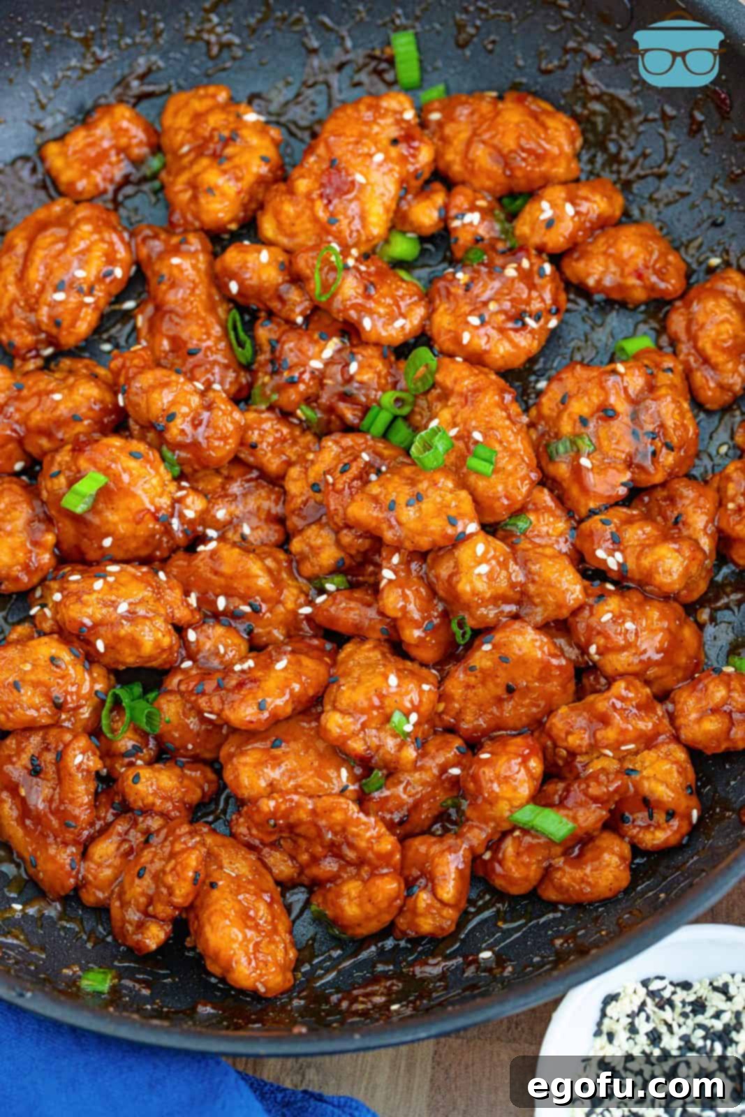 A final, mouth-watering shot of Easy General Tso's Chicken in a skillet, beautifully garnished with fresh scallions and toasted sesame seeds, steaming hot and ready to be served.