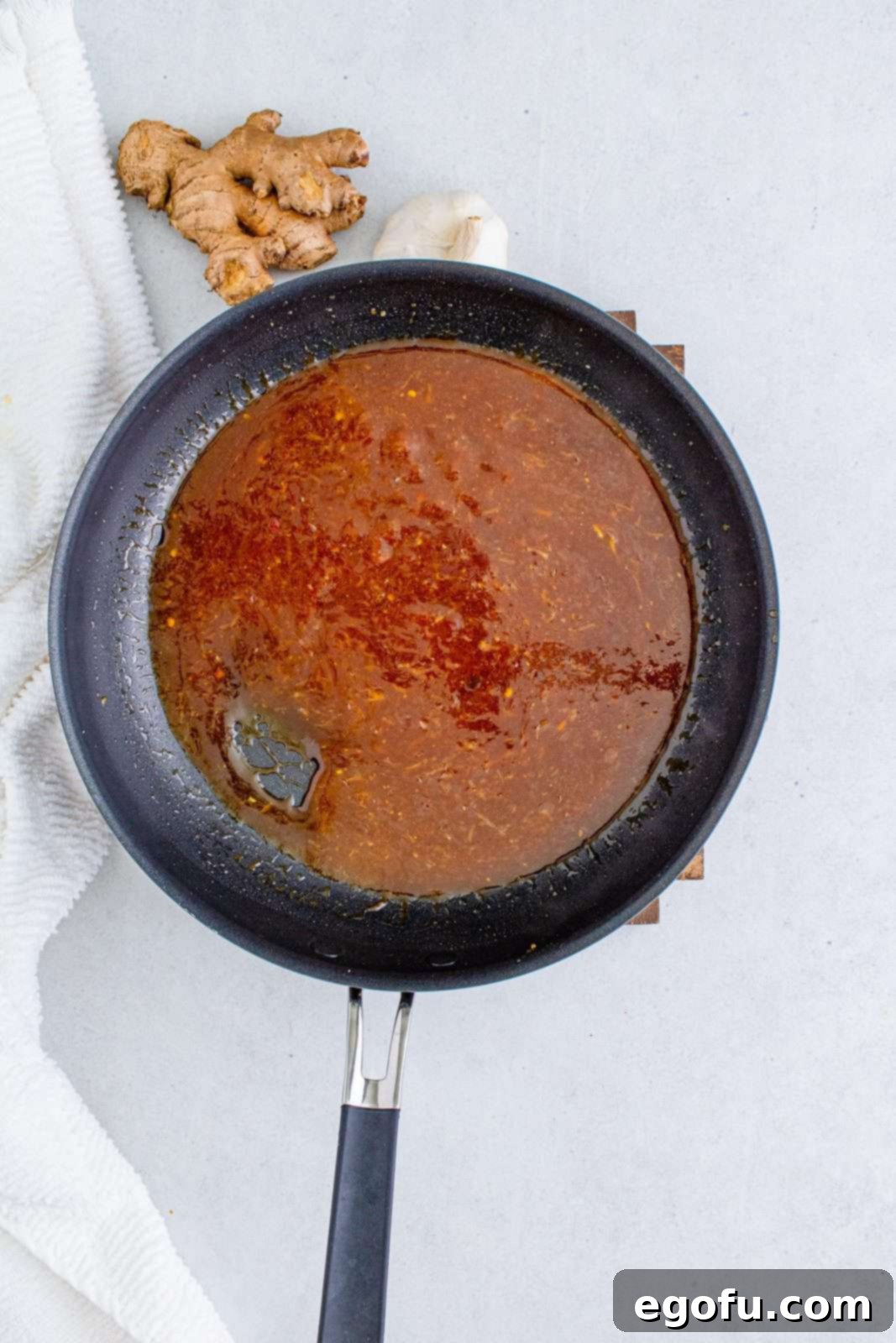 The whisked General Tso's sauce mixture poured into the pan with the aromatic paste, simmering and thickening to a rich, glossy consistency, ready for the chicken.