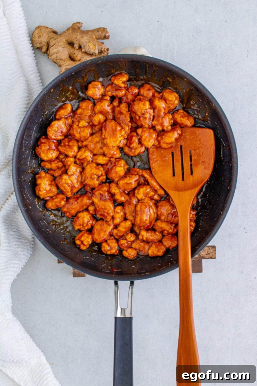 Chicken fully tossed and coated in the glossy General Tso's sauce in the pan, highlighting its rich color and inviting texture.