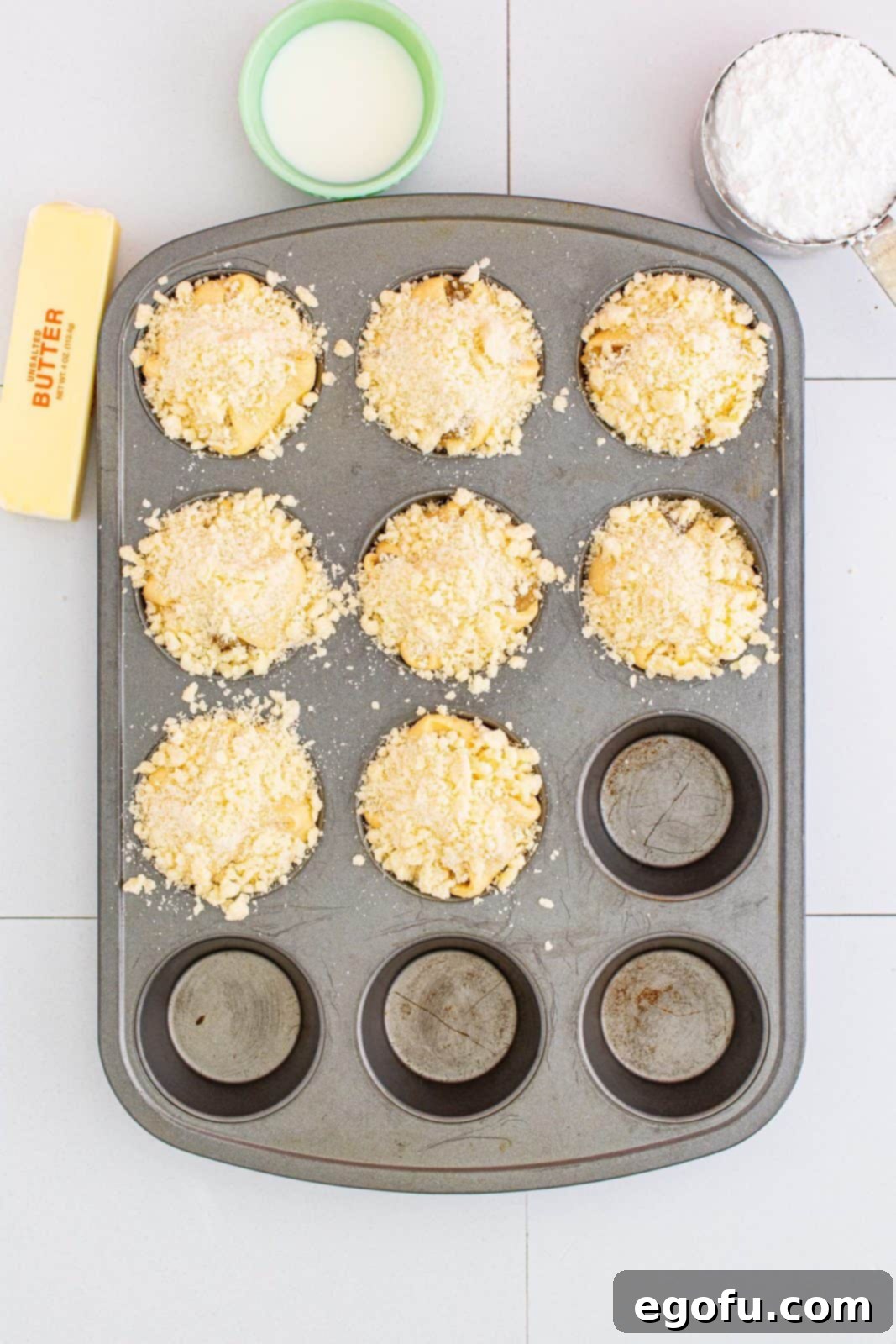Quick Apple Pie Bites 12 Crumble topping generously added to the top of the folded crescent squares with apple filling, ready for baking.