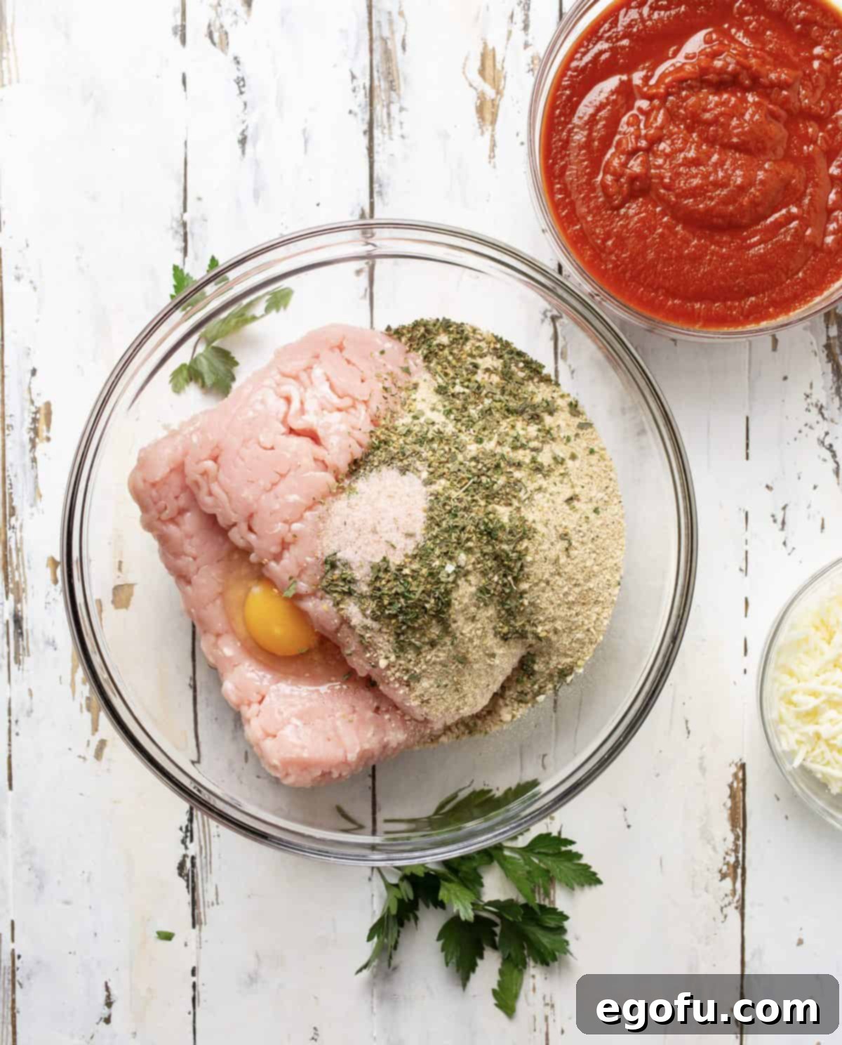 Ground turkey, italian breadcrumbs, eggs, italian seasoning and salt added to clear bowl.