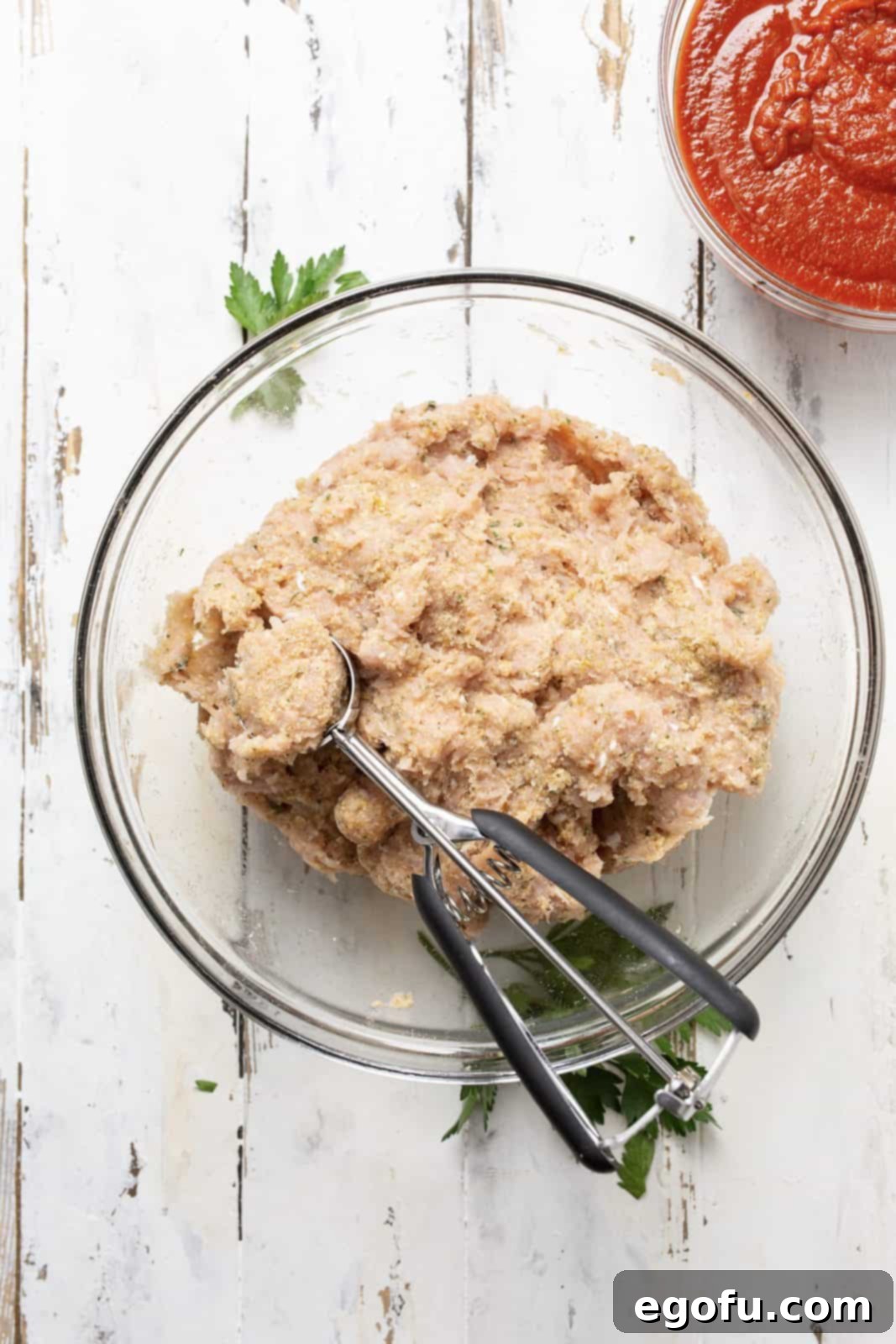 Mixed up meatball mixture with scoop for portioning.