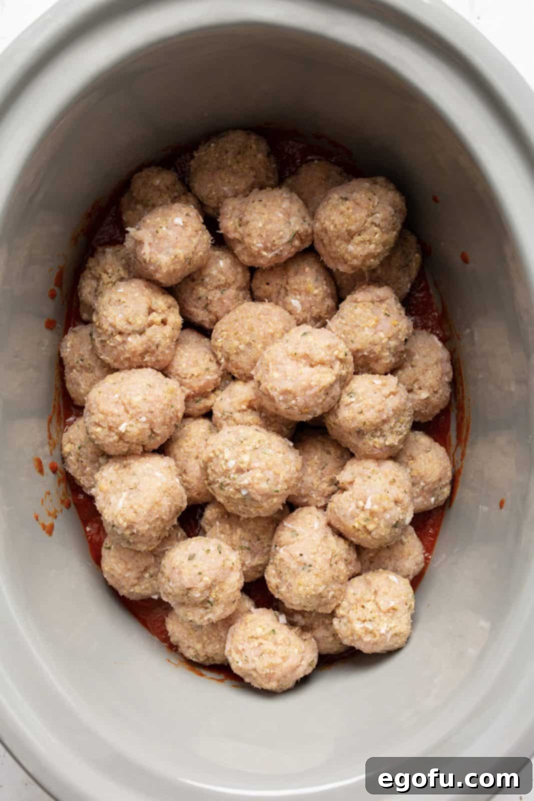 Meatballs in crock pot over a layer of sauce.