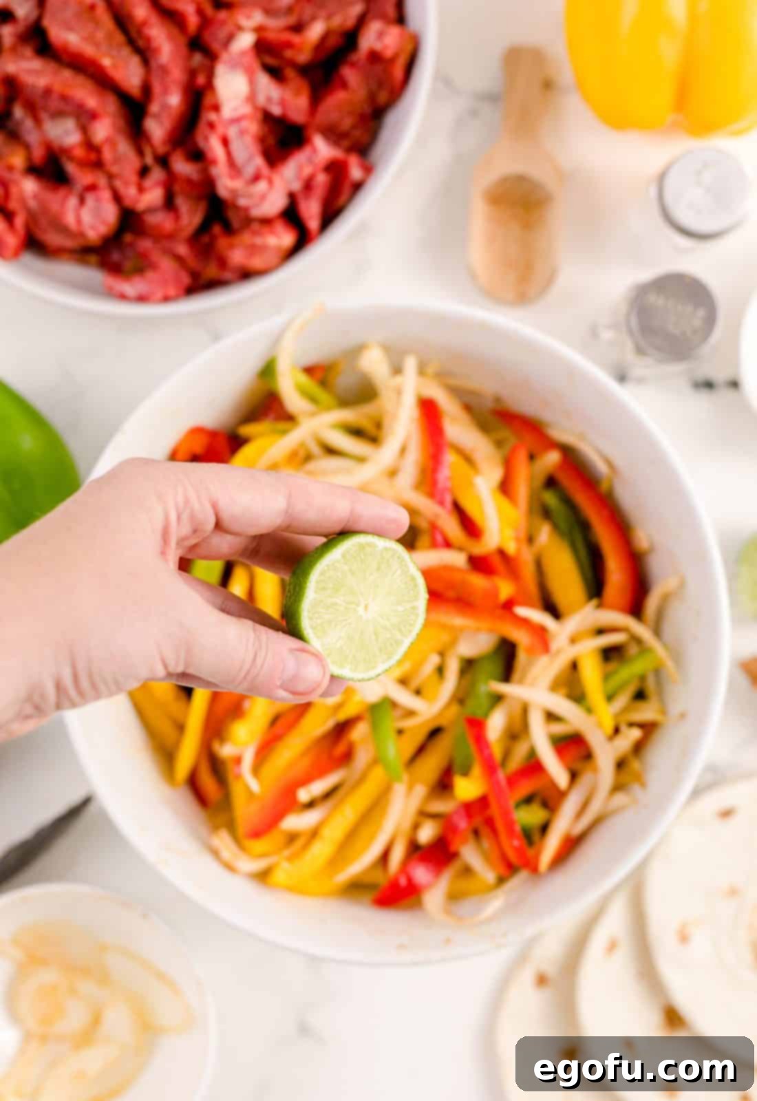 Fresh lime juice being squeezed over the seasoned vegetables in a bowl, adding a zesty finish.