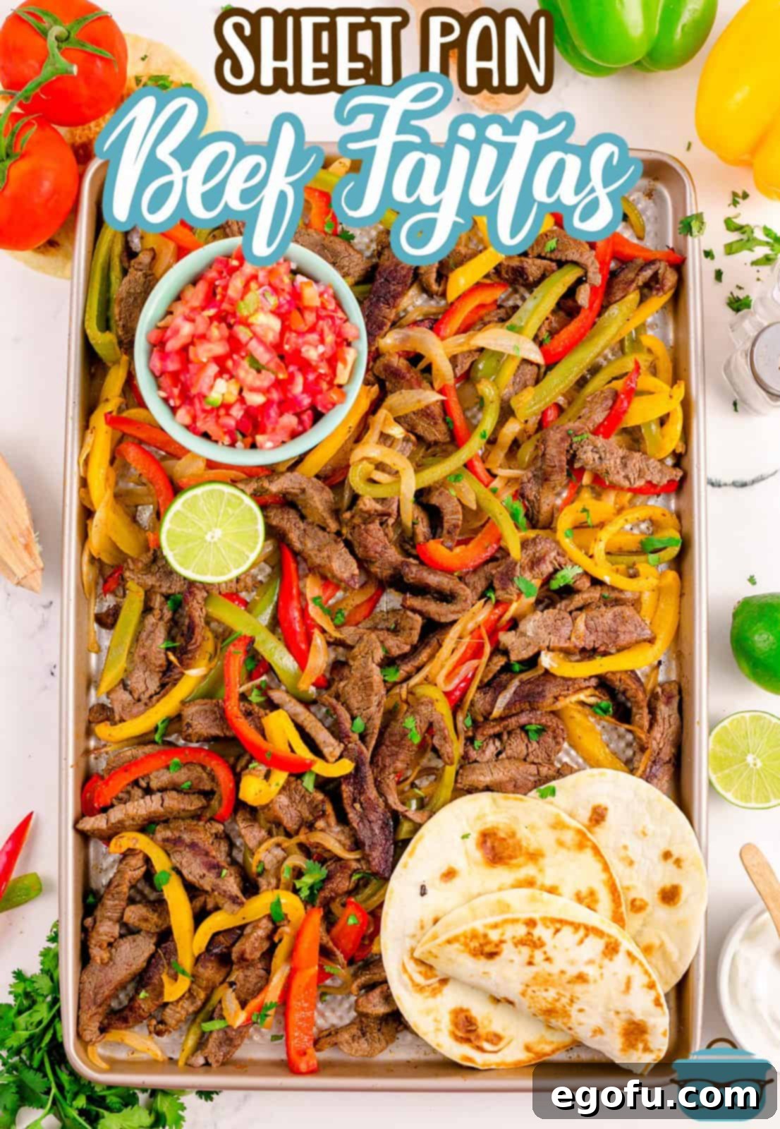 Overhead view of a Sheet Pan Beef Fajitas dinner, with seasoned beef, colorful bell peppers, and onions mixed together on the pan.