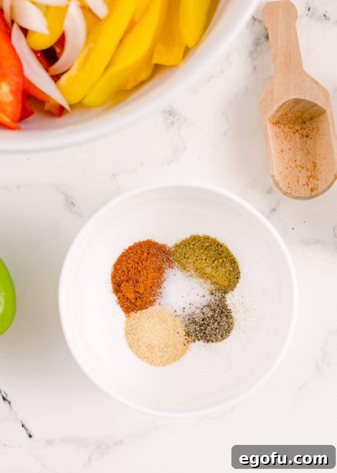 A small bowl containing a homemade fajita spice blend: salt, pepper, cumin, chili powder, and garlic powder.