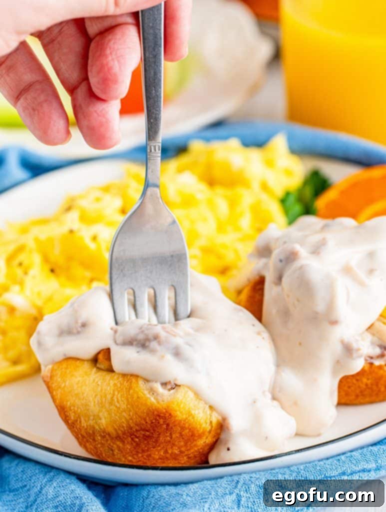 Biscuits and Gravy Cups on plate with gravy over top and fork going into one cup.