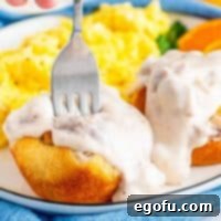 Square image of Biscuits and Gravy Cups with gravy over top on plate with plate going into one cup.