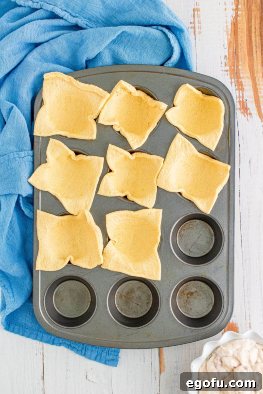 Cut up crescent dough sheet in squares placed in prepared muffin pan.