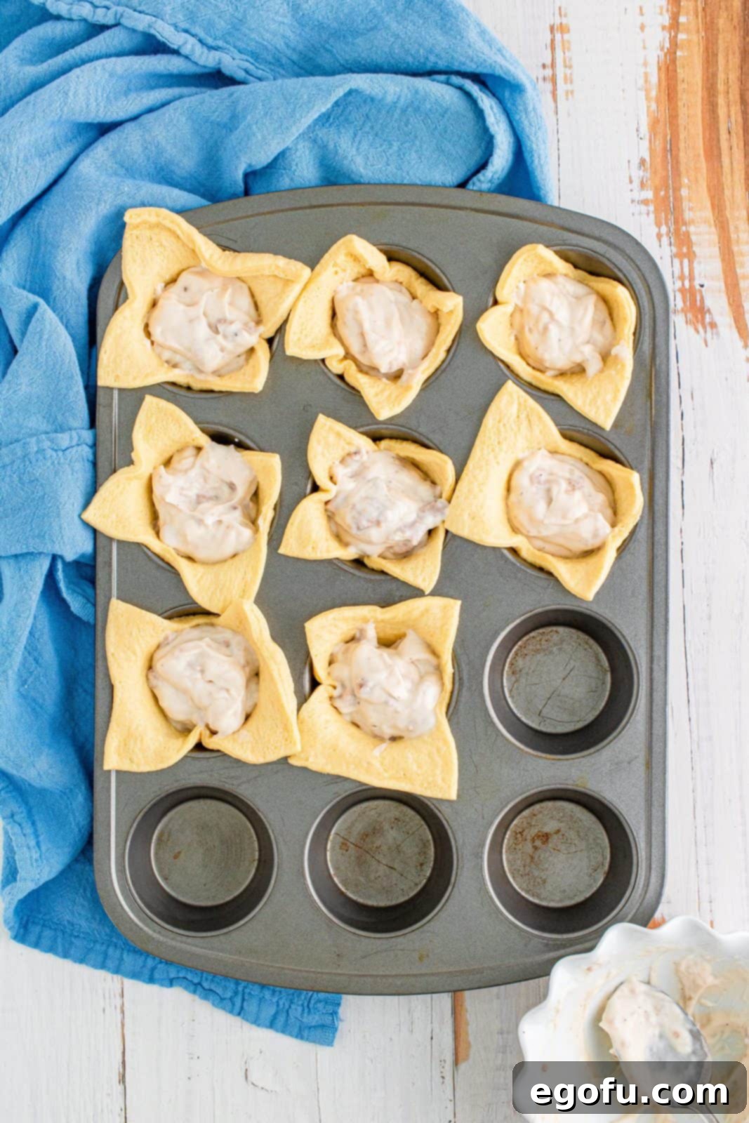 Gravy added to crescent squares in muffin pan.