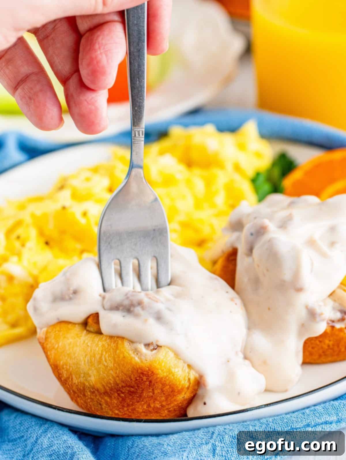 Biscuits and Gravy Cups on plate with gravy over top and fork going into one cup.
