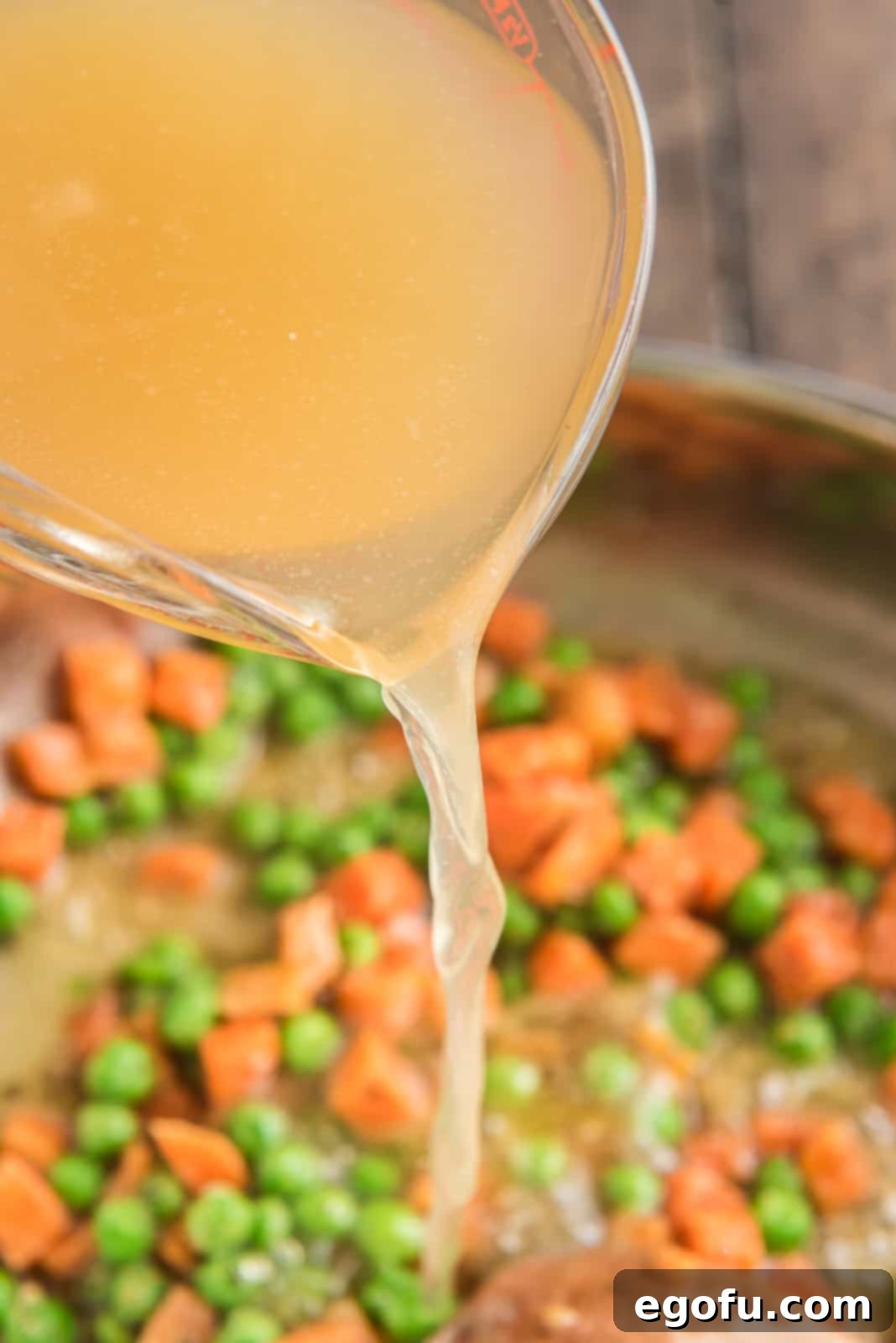 Chicken stock and cream of chicken soup added to skillet with vegetables and roux.