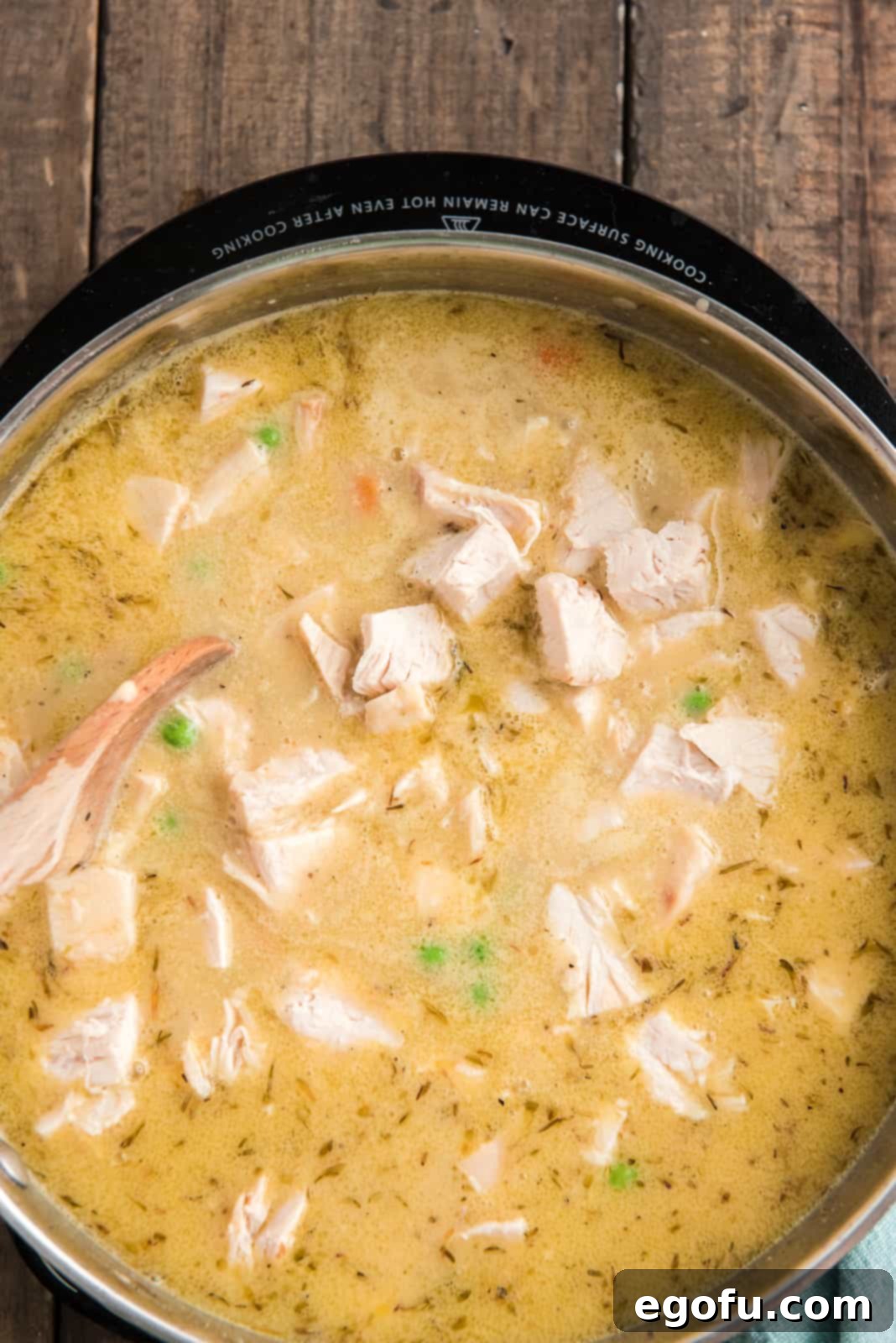 Diced rotisserie chicken added to the creamy sauce in the skillet, being stirred to coat.