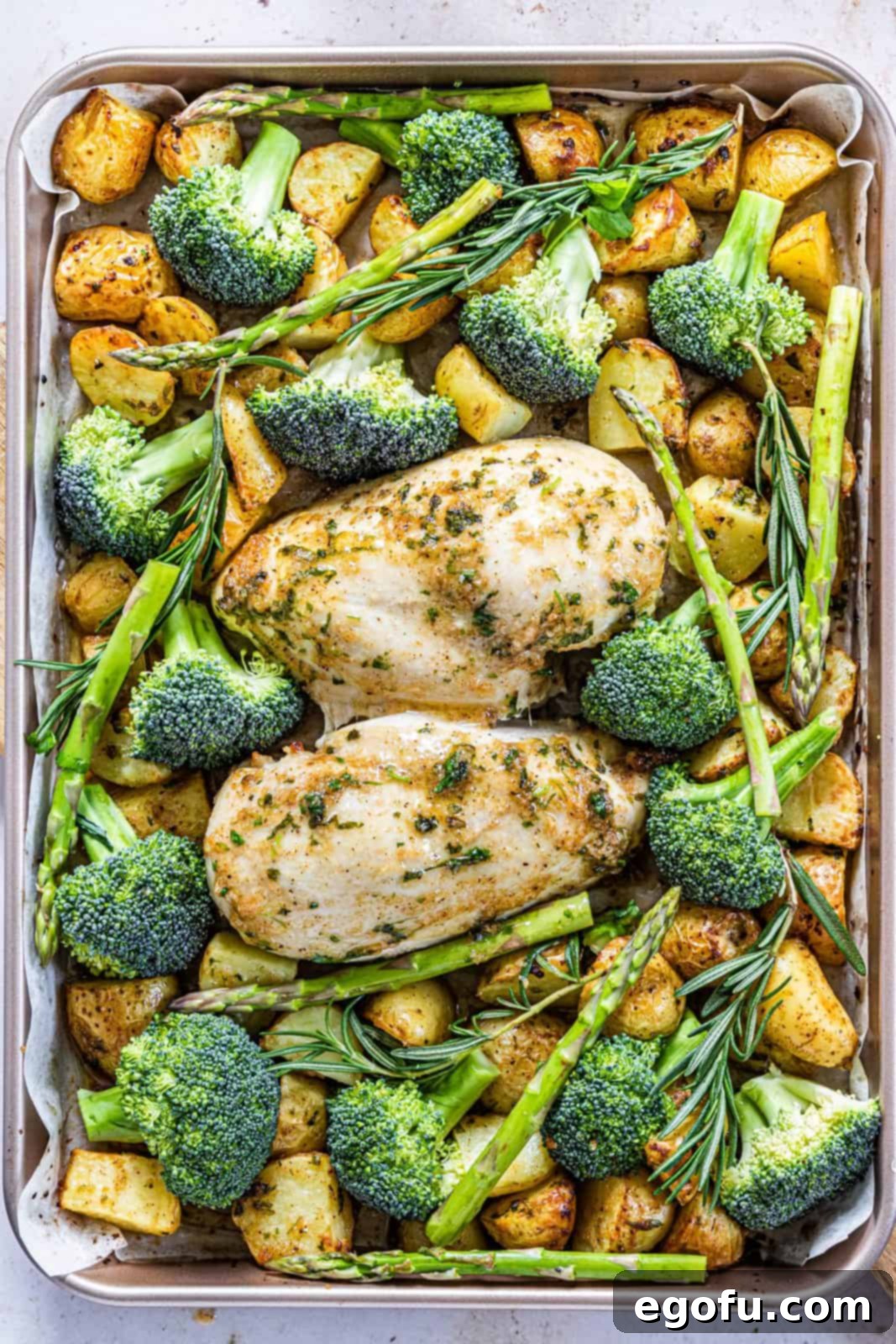 Garlic Butter Sheet Pan Chicken Dinner 12 Asparagus, broccoli and rosemary added to pan with chicken and potatoes.
