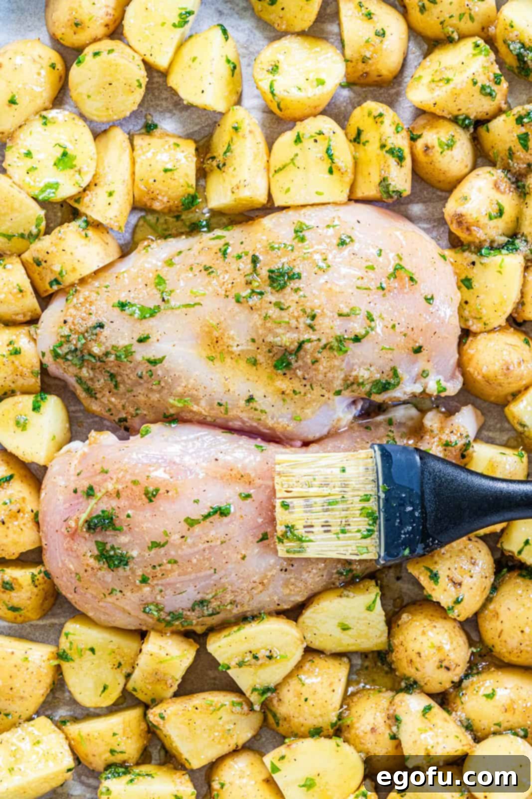 Garlic Butter Sheet Pan Chicken Dinner 10 Chicken and vegetables being brushed with garlic butter mixture.